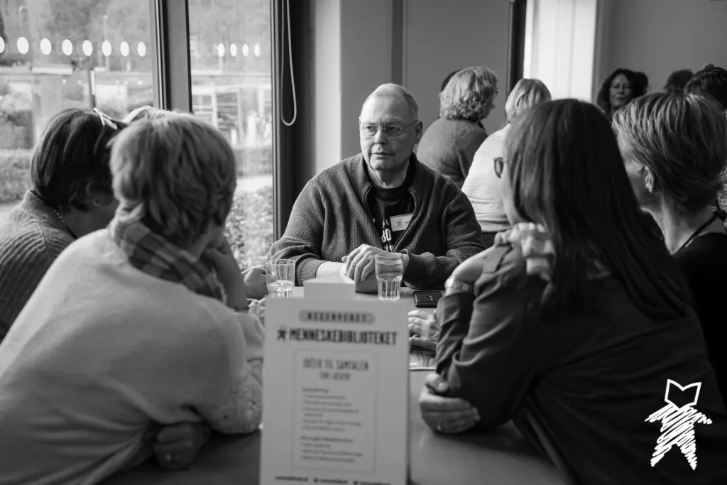 Menschen, die sich an Tischen interessiert miteinander unterhalten.